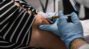 Gloved healthcare worker administers vaccine in patients arm