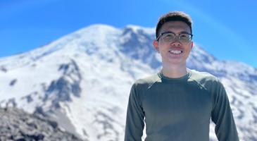 Photo of Xiudi Li standing in front of snowy peak.