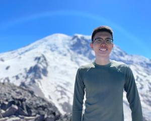 Photo of Xiudi Li standing in front of snowy peak.